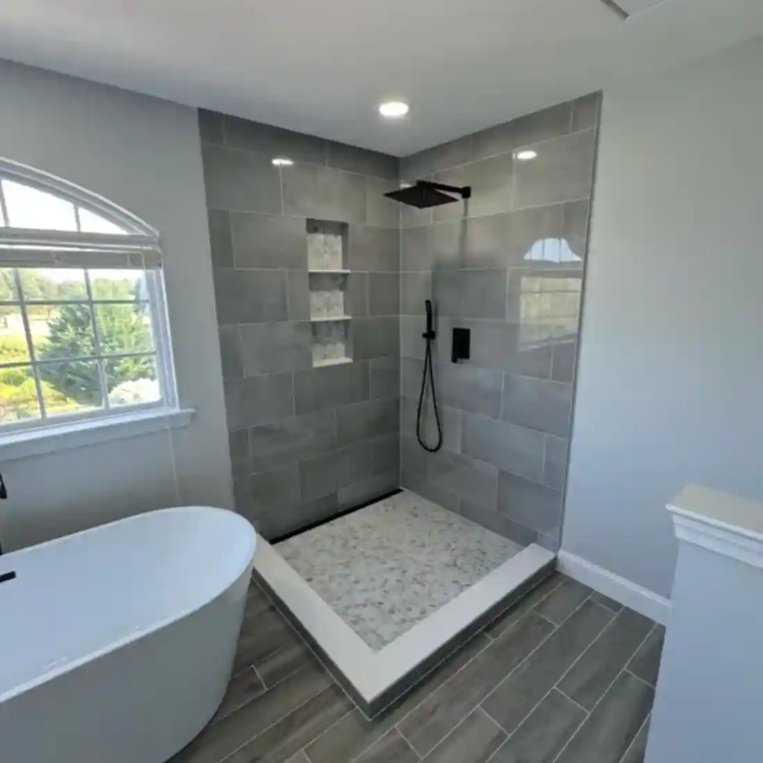 Contemporary bathroom with gray tile shower and freestanding tub